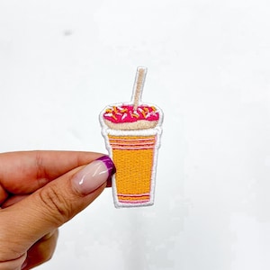 May include: An embroidered iron-on patch of a pink and white donut with sprinkles on top of a yellow and pink striped cup with a white straw.