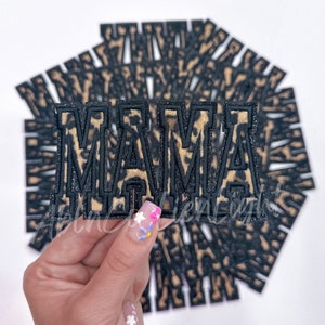 May include: A stack of black and brown leopard print iron-on patches that spell out "MAMA".