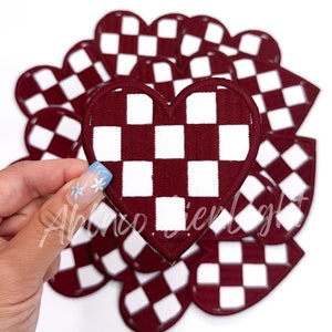 May include: A set of 10 red and white checkered heart-shaped patches. The patches are made of fabric and have a soft, fuzzy texture.