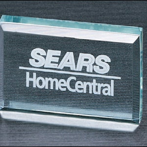 May include: A clear glass paperweight with the words "SEARS HomeCentral" etched in white.