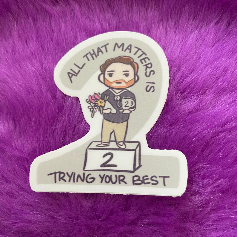 K&ouml;nnte beinhalten: Eine Cartoon-Illustration einer Person, die eine Troph&auml;e und Blumen h&auml;lt und auf einem Podest mit der Nummer 2 steht. Der Text "All that matters is trying your best" ist um das Bild herum geschrieben.