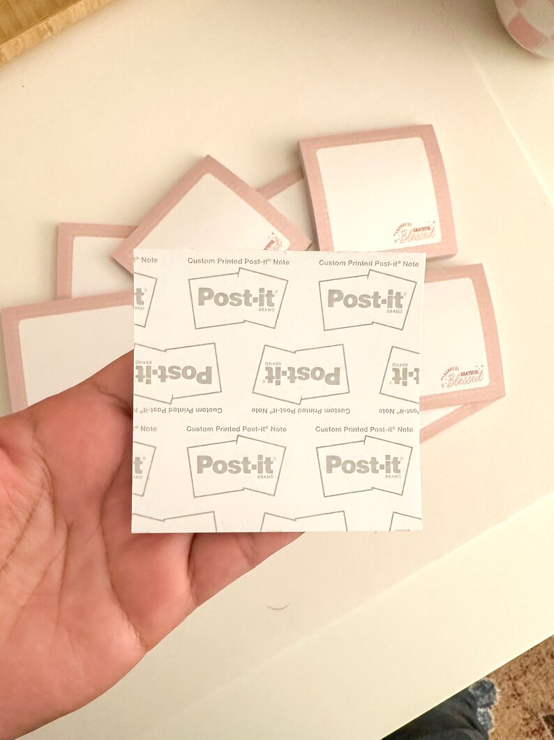 May include: A stack of pink Post-it notes with the text "Custom Printed Post-it Note" and the Post-it logo. The notes are blank and ready to be written on.