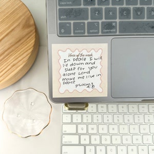 May include: A pink sticky note with rounded corners and a decorative border on a laptop keyboard. The note has the text "Verse of the week" at the top and the following text below: "In peace I will lie down and sleep for you alone Lord make me live in peace Psalms 4:8"