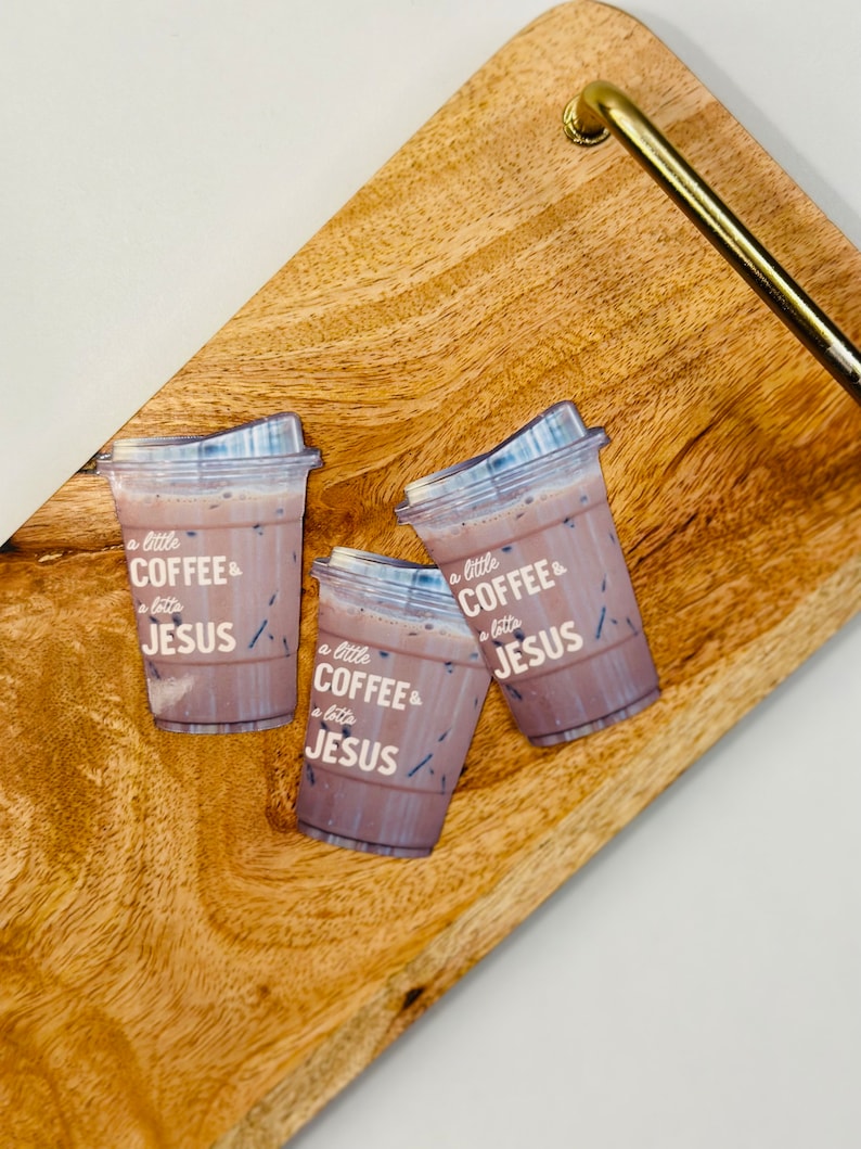 May include: Three iced coffee cups with the text "a little coffee & a lotta jesus" on a wooden serving tray.