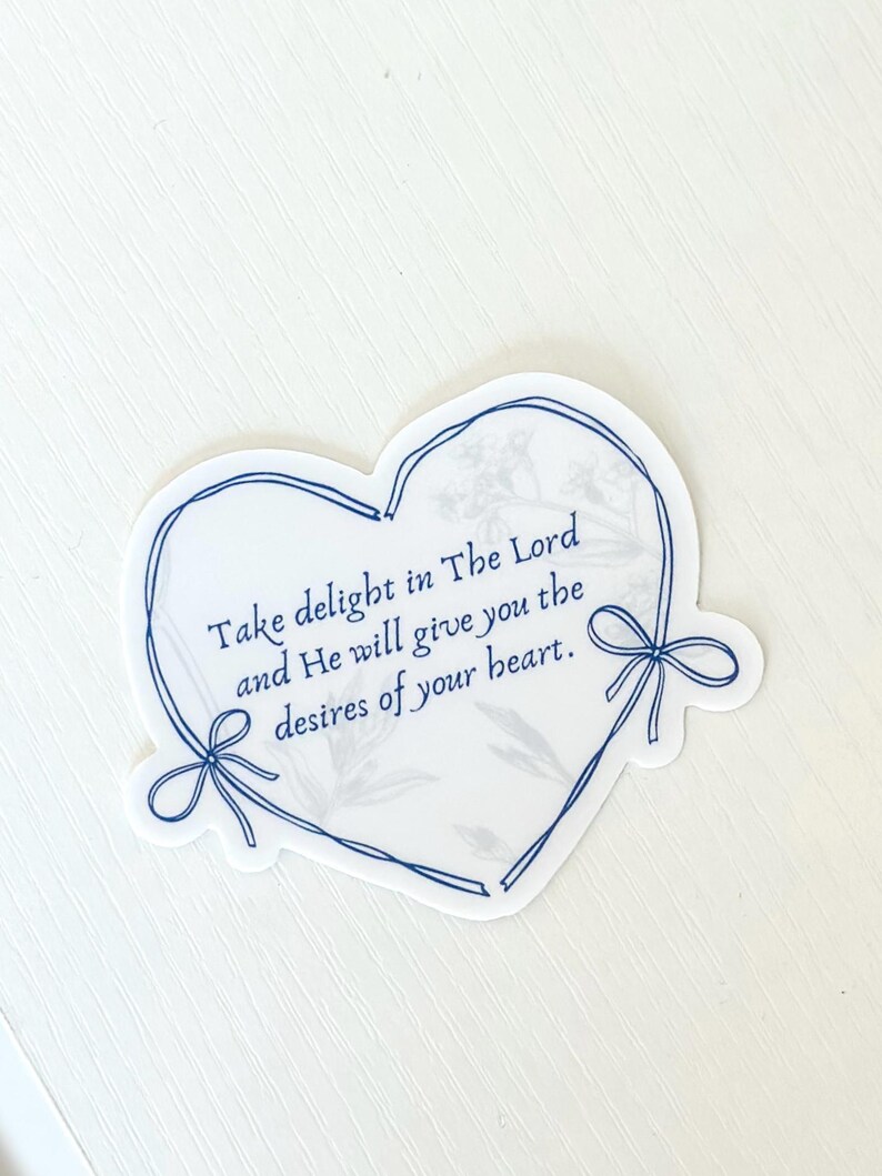 May include: A white heart-shaped sticker with a blue outline and a floral pattern. The sticker has the text "Take delight in The Lord and He will give you the desires of your heart."
