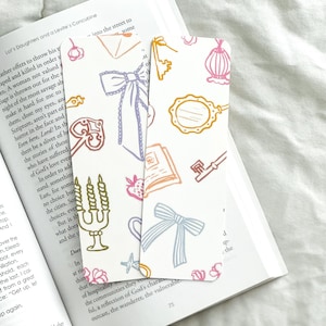 May include: Two colorful bookmark designs with a white background. The bookmarks feature various illustrations of keys, bows, candles, envelopes, and stars. The text "into the street to some" is visible on one of the bookmarks.