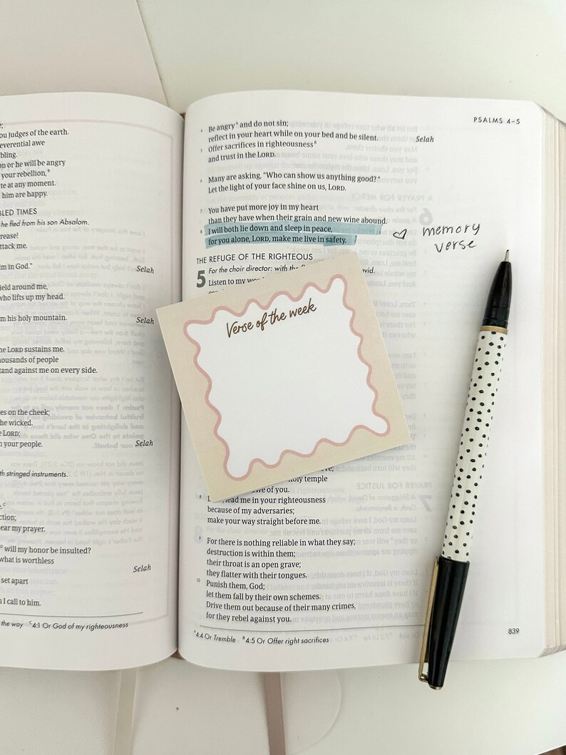 May include: A close-up of a pink sticky note with the text "Verse of the week" written in a white circle. The sticky note is placed on a page of an open Bible with the text "The Refuge of the Righteous" highlighted. The Bible is open to Psalms 4-5.