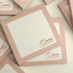 May include: Pink sticky notes with a grid pattern and the text "Thankful Grateful Blessed" in gold lettering.
