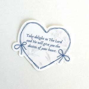 May include: A heart-shaped sticker with a blue outline and a floral design. The sticker features the text "Take delight in The Lord and He will give you the desires of your heart."