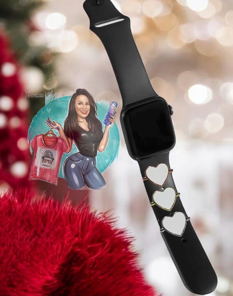 Op de afbeelding: Een zwarte Apple Watch met een zwarte band en drie zilveren hartvormige bedels. Het horloge is op een witte achtergrond.