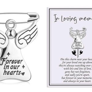 May include: A silver angel pin with outstretched wings, attached to a safety pin. The angel has the words "Forever in our hearts" inscribed. A card next to it reads "In Loving memory".