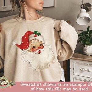 Op de afbeelding: Beige sweatshirt met een vintage kerstman ontwerp. De kerstman afbeelding heeft een rode hoed, witte baard en een lachend gezicht. De sweatshirt wordt getoond als een voorbeeld van hoe het ontwerpbestand kan worden gebruikt.