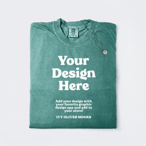 May include: A teal green t-shirt with the text "Your Design Here" and the text "Add your design with your favorite graphic design app and add to your store! IVY OLIVER MOCKS" printed on the front.