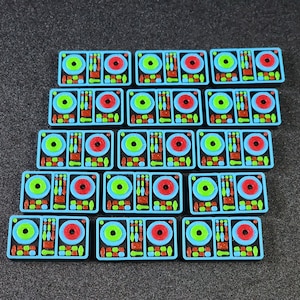 May include: A set of 15 blue, black, red, and green plastic toy DJ mixers. Each mixer has two round knobs, a slider, and a button.