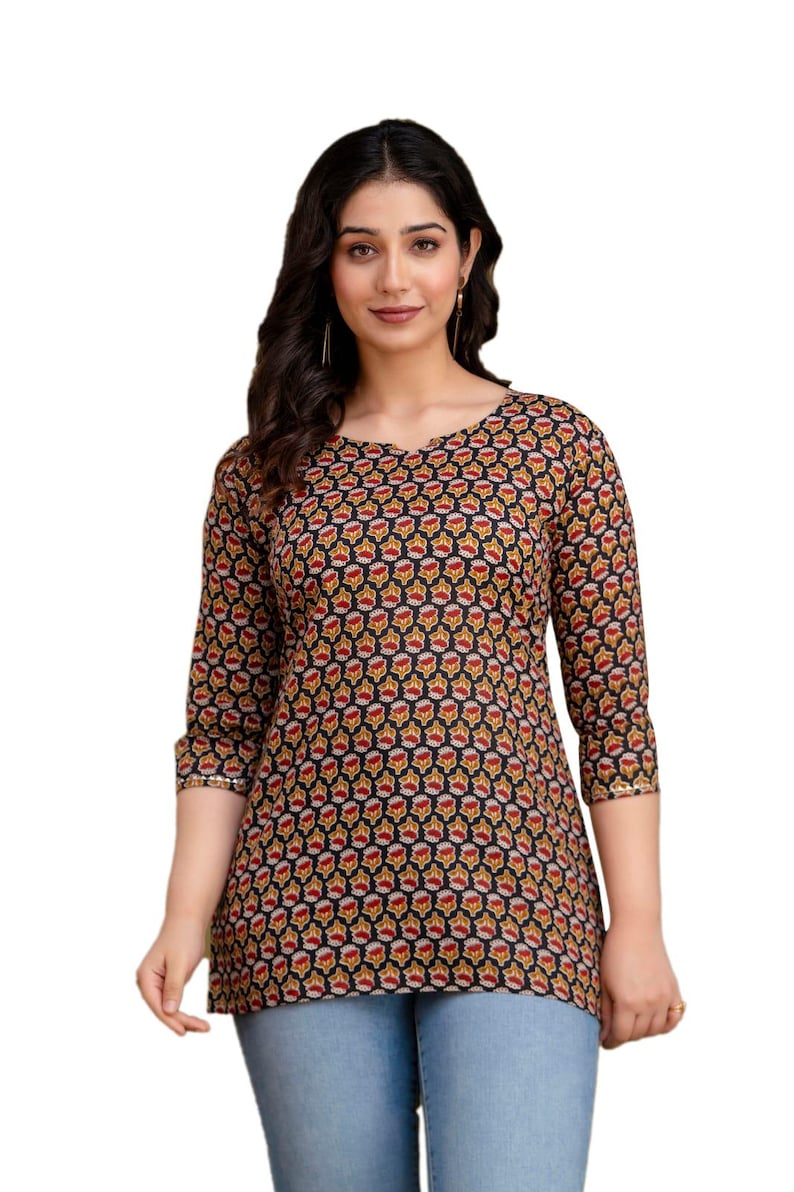 Puede incluir: Top de manga tres cuartos con estampado floral en rojo, amarillo y blanco sobre fondo negro. El top tiene cuello redondo y se combina con vaqueros azul claro. Las mangas tienen detalles dorados.