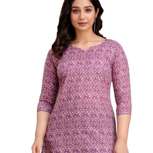 Puede incluir: Una blusa morada con un estampado geom&eacute;trico. La blusa tiene cuello en V y mangas tres cuartos. La tela presenta un patr&oacute;n repetido de diamantes en tonos morados, amarillos y blancos. La blusa se combina con vaqueros azules.