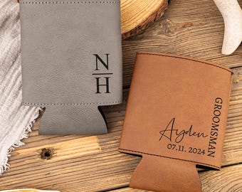 May include: Two personalized can coolers. One is gray with the initials "N H" and the other is brown with the name "Ayden" and the date "07.11.2024" and the word "Groomsman".