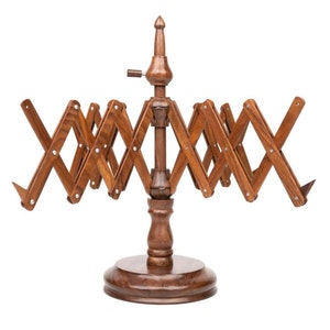 Pode incluir: Um suporte de fio de madeira com um design dobrável. O suporte tem um poste central com um botão no topo e uma base circular. Os braços do suporte são de madeira e dobram para criar uma forma de estrela.