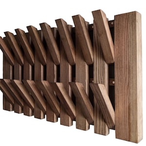 May include: A wooden coat rack with a unique design featuring multiple angled wooden hooks. The rack is made of dark brown wood and has a rustic appearance.