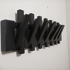 Può includere: Appendiabiti da parete in legno nero con più ganci angolari.