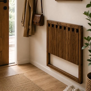 May include: A wall-mounted, rectangular wooden folding chair featuring a dark brown wood grain finish. The chair is designed with vertical slats and a frame that allows it to fold flat against the wall when not in use, providing a space-saving solution.