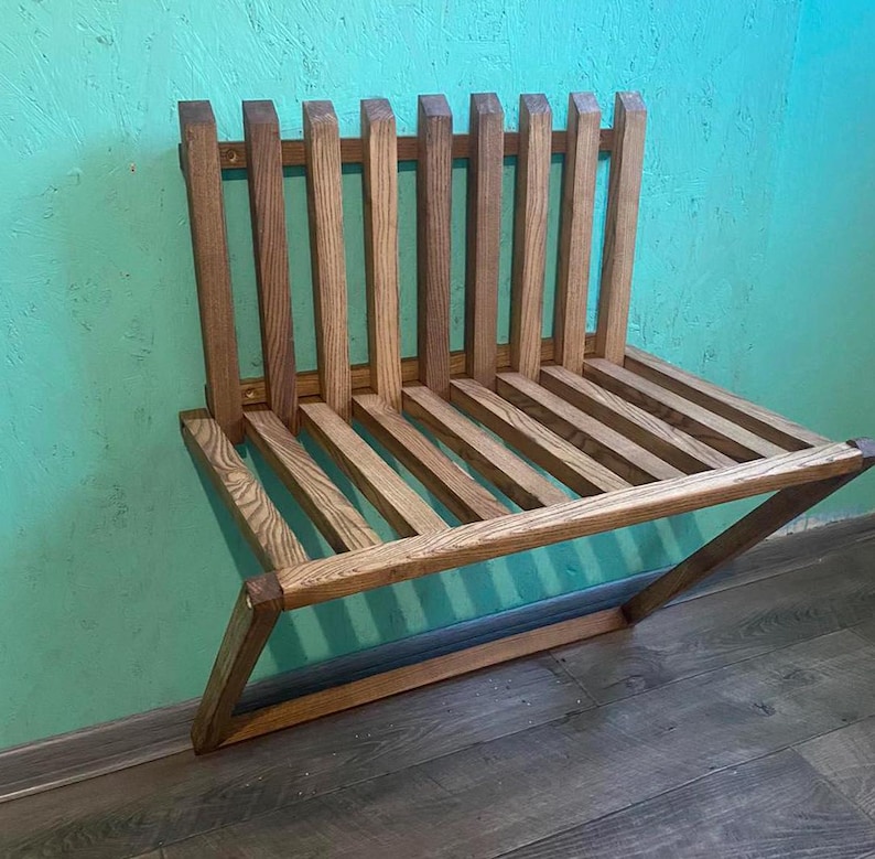 May include: A wooden wall-mounted bench with a slatted design. The bench is made of natural wood with a light brown finish.