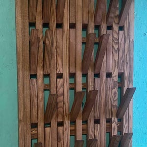 Può includere: Un appendiabiti da parete in legno con un design geometrico unico. L'appendiabiti è realizzato con più pezzi di legno disposti in uno schema sfalsato per creare un aspetto moderno ed elegante.