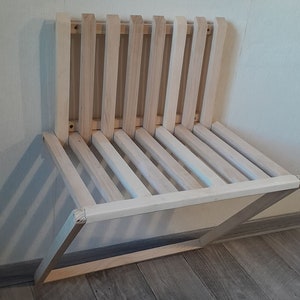 May include: A light wood folding wall-mounted bench with a slatted seat and back.