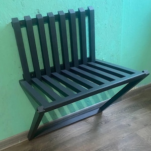 May include: A black metal wall-mounted bench with a slatted seat and a simple, modern design.