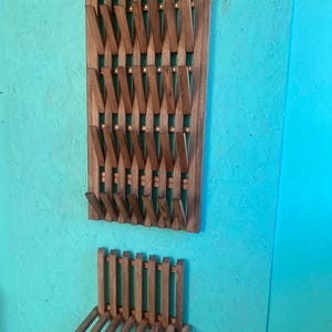 May include: A wooden coat rack with a slatted design and a matching wooden bench. The rack has multiple hooks for hanging coats, hats, or bags. The bench is a simple design with a slatted seat and legs.