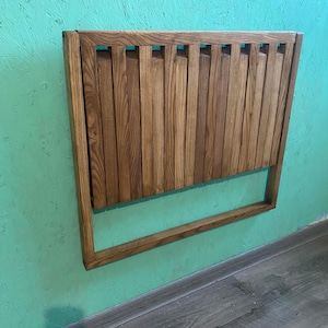 May include: A wooden wall-mounted folding table with a light brown stain. The table is made of slats and has a simple design.