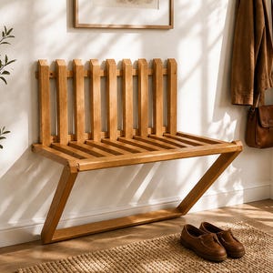 May include: A wooden bench with a slatted seat and back, and angled legs. The bench is made of light-coloured wood and is positioned against a white wall. Brown leather shoes sit on a woven rug in front of the bench.