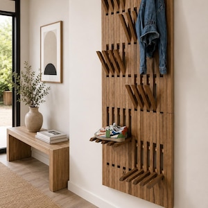May include: Wooden wall-mounted coat rack with multiple hooks and a shelf. A blue denim jacket hangs on the rack. A pair of colorful trainers rests on the shelf. The rack is in a hallway setting.