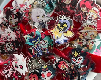 Puede incluir: Una colección de llaveros acrílicos con varios personajes de dibujos animados con colores vibrantes y diseños detallados. Cada llavero tiene un anillo de metal plateado para sujetar. Los personajes tienen una variedad de expresiones y poses.