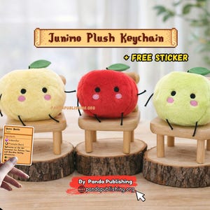 Puede incluir: Tres llaveros de peluche Junimo en amarillo, rojo y verde, cada uno con una pequeña silla de madera y una base de madera. Los llaveros tienen brazos y piernas negros y mejillas rosadas. El texto "Junimo Plush Keychain" se muestra arriba.