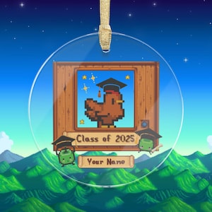 Peut inclure: Ornement rond et transparent avec un ruban doré. Il présente un poulet pixélisé portant une toque de diplômé, avec le texte "Class of 2025" et un espace pour un nom. L'arrière-plan montre un ciel nocturne et des collines vertes.