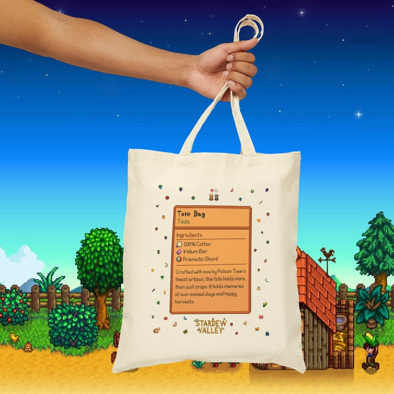 Puede incluir: Una bolsa de lona blanca con el logotipo de Stardew Valley y una receta para una "Tote Bag" con los ingredientes 100% algod&oacute;n, barra de iridio y fragmento prism&aacute;tico. El texto dice "Elaborado con amor por los artesanos m&aacute;s finos de Pelican Town, esta bolsa contiene m&aacute;s que solo cultivos. Contiene recuerdos de d&iacute;as soleados y cosechas felices."