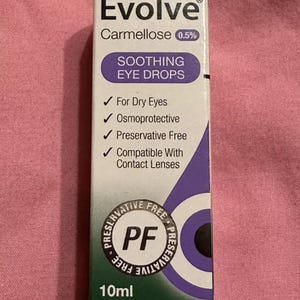 Puede incluir: Una caja blanca y morada de Evolve Carmellose 0,5% Soothing Eye Drops. La caja incluye el texto "For Dry Eyes", "Osmoprotective", "Preservative Free" y "Compatible With Contact Lenses". La caja contiene 10 ml de producto.