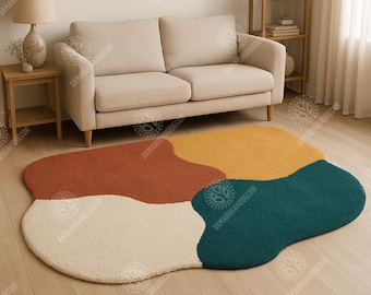 Könnte beinhalten: Ein mehrfarbiger, abstrakter Teppich mit einer weichen, strukturierten Oberfläche. Der Teppich hat vier verschiedene Bereiche in Creme, Rost, Gold und Blaugrün. Der Teppich liegt auf einem hellen Holzboden, mit einem beigen Sofa und Holzmöbeln im Hintergrund.