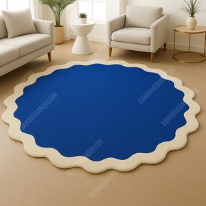 May include: A round rug with a wavy edge. The rug has a bright blue center and a cream-colored border. The rug is placed on a light brown hardwood floor. The rug is a decorative item for a living room.