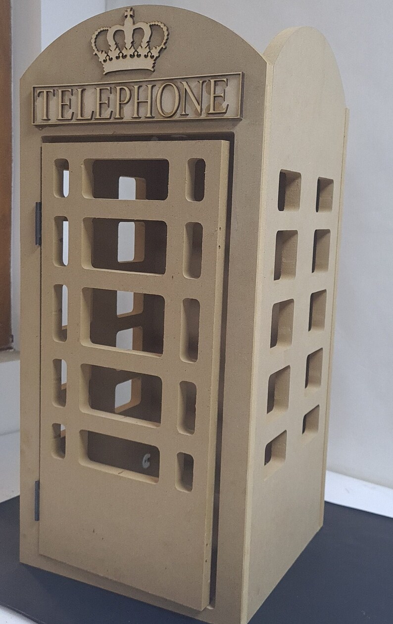 May include: A brown wooden model of a classic British telephone box with a crown on top and the word "TELEPHONE" inscribed on the front.