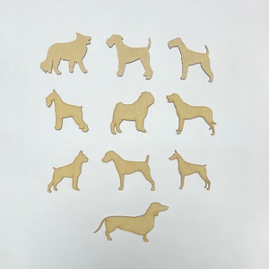 May include: Eleven wooden dog silhouettes in different breeds, such as a dachshund, terrier, and boxer. The dogs are cut from light brown wood and arranged on a white background. Suitable for crafting or pet-themed decorations.