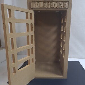 May include: A wooden model of a red British telephone box with a crown on top and the word "TELEPHONE" on the front. The door is open and the inside is empty.