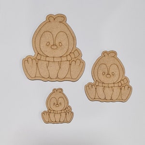 May include: Three unfinished wooden penguin ornaments of varying sizes. The penguins are wearing scarves and have simple facial features.