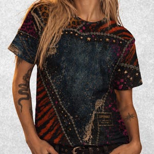 Può includere: Una t-shirt a maniche corte con un design patchwork che unisce denim blu scuro, stampa leopardata e strisce tigrate rosse. La maglia presenta un pannello centrale stellato, cuciture decorative e una piccola etichetta con SUPERNAUT.