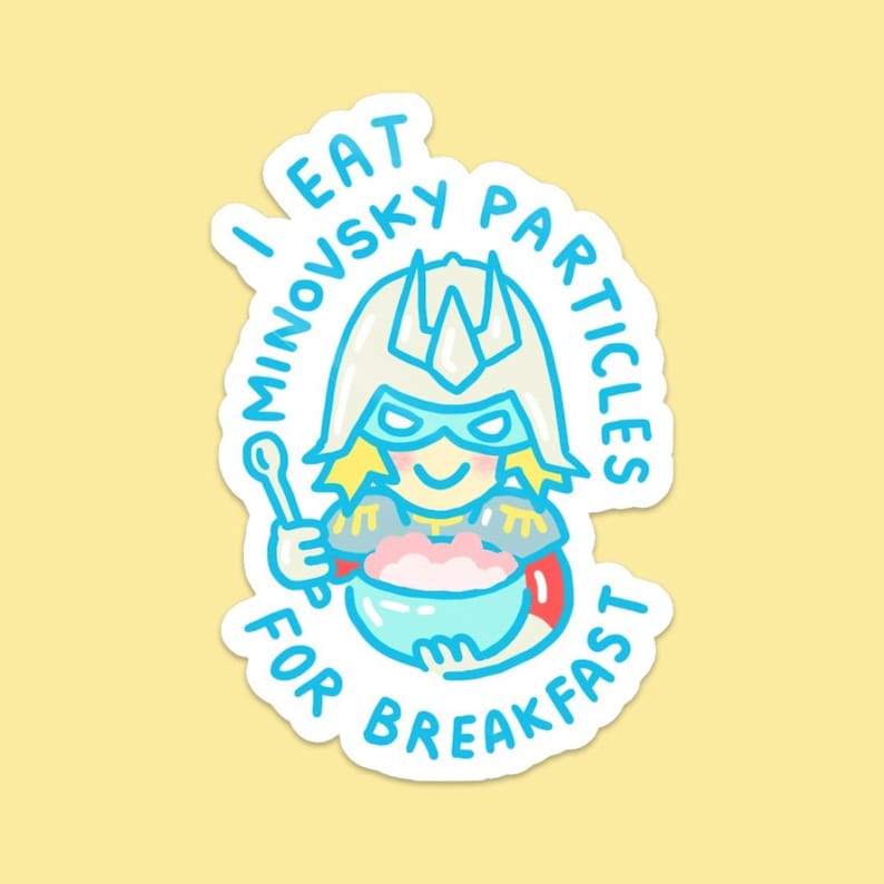 Pu&ograve; includere: Un adesivo con un personaggio di supereroe dei cartoni animati con una maschera e un elmetto blu, che tiene un cucchiaio e una ciotola di cibo rosa. Il testo "I EAT MINOVSKY PARTICLES FOR BREAKFAST" &egrave; scritto intorno al personaggio in blu.