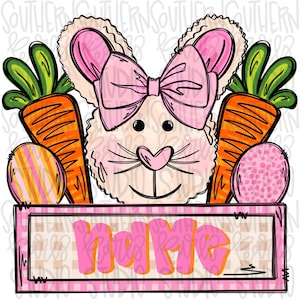 Könnte beinhalten: Ein rosa Kaninchen mit einer rosa Schleife und einer Karotte im Maul. Das Kaninchen hält ein Schild mit der Aufschrift "name".