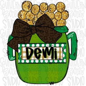 Puede incluir: Un tarro de vidrio verde con un lazo marrón y estampado de leopardo. El tarro está lleno de monedas de oro y tiene una etiqueta a cuadros blancos y verdes con el nombre "Demi" en ella.