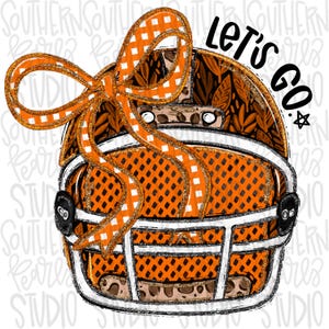 May include: A football helmet graphic featuring an orange and white checkered bow on the side. The helmet has a black and orange leaf pattern, a bright orange mesh texture, and a white face mask. The text LET'S GO is printed in black above.