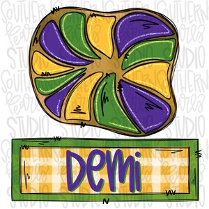 May include: A purple, green, and gold king cake with the word "Demi" written on a yellow and white checkered sign.